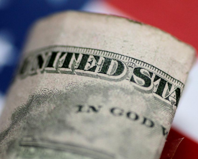 A dollar bill help up against the american flag simbolizing the u.s economy